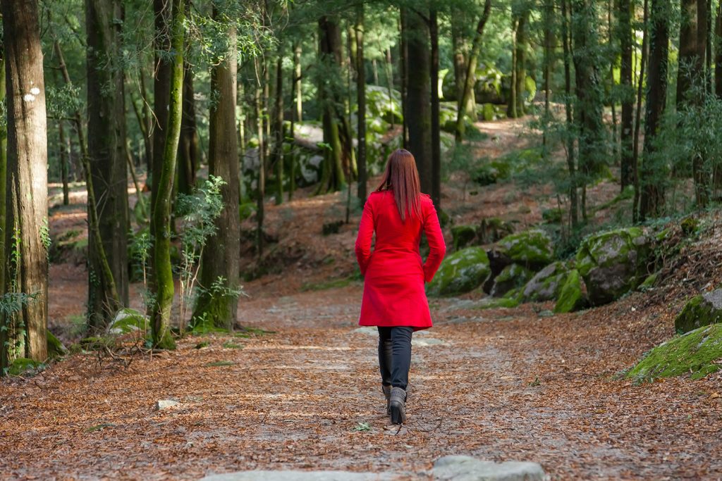Woman walking away on a path in a red coat