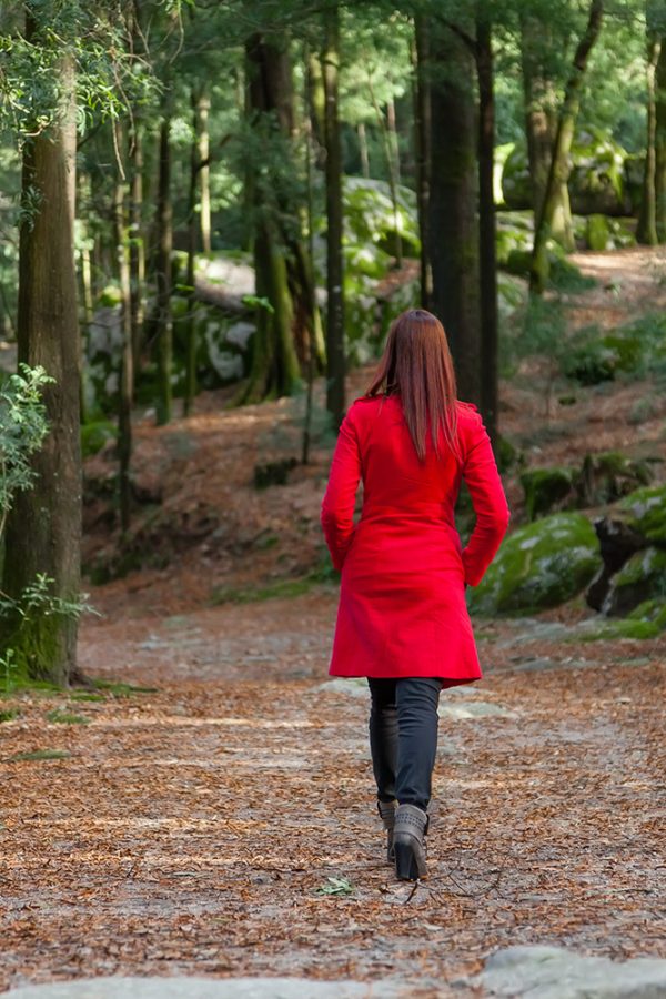 Woman walking away on a path in a red coat